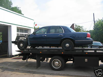 2005 Ford Crown Victoria - A blue 2005 Ford Crown Victoria is being transported on a flatbed tow truck.