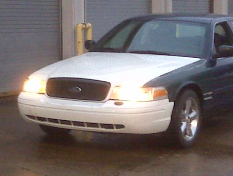 2005 Ford Crown Victoria - Front view of a 2005 Ford Crown Victoria with its headlights illuminated.