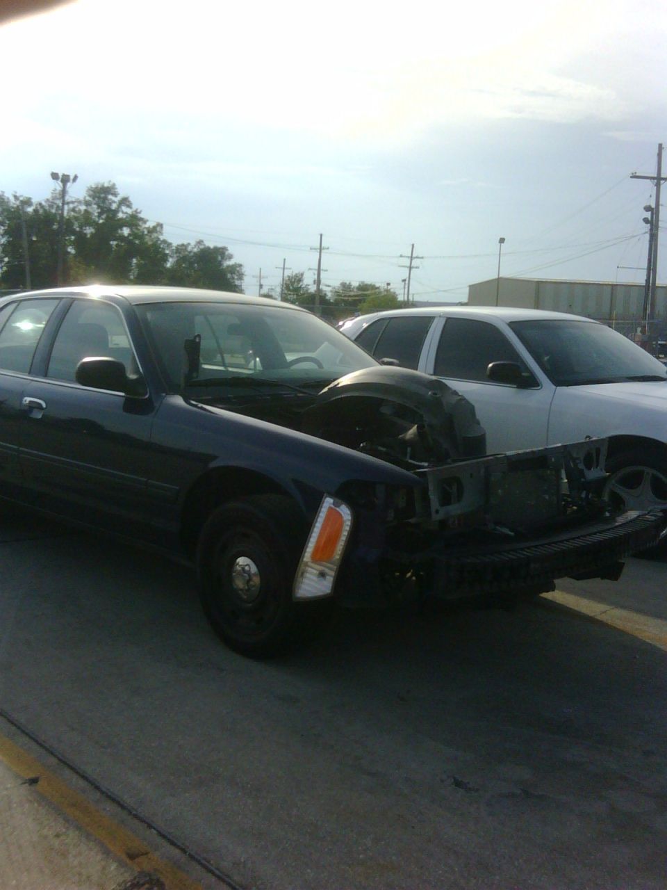 Dark blue 2005 Ford Crown Victoria with hood open and front end missing