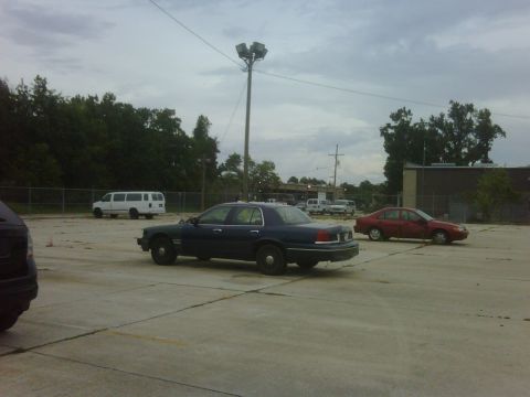 2005 Ford Crown Victoria - A dark blue sedan is parked in a lot with other vehicles under a cloudy sky.