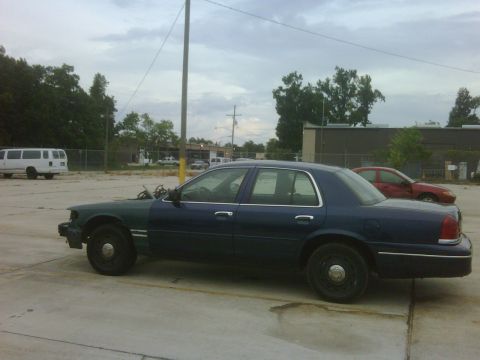 2005 Ford Crown Victoria - This 2005 Ford Crown Victoria is seen from the side, showing a two-tone paint job and exposed engine parts.