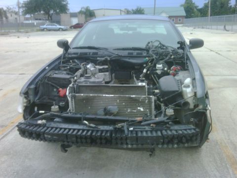 2005 Ford Crown Victoria - A damaged Ford Crown Victoria sits with its hood open, revealing the exposed radiator and engine components.