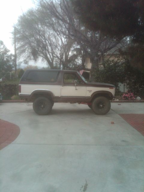 1982 Ford Bronco - Side view of a lifted Ford Bronco SUV with a two-tone paint scheme.
