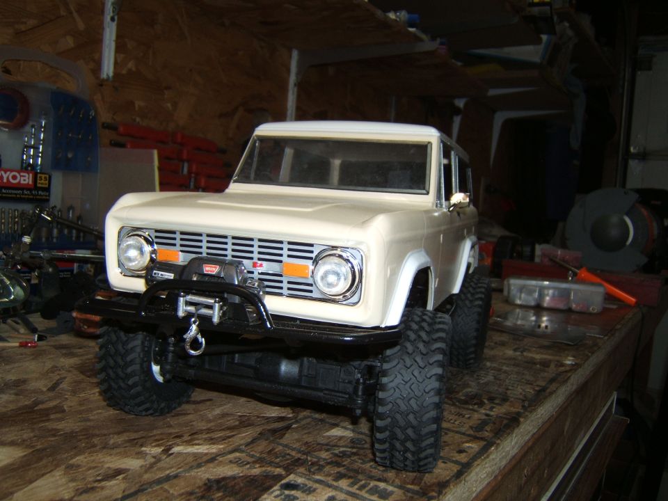 Cream-colored RC car model with a winch on the front bumper, parked on a wooden surface
