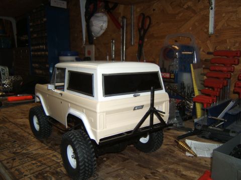 1988 Ford Bronco - A remote-controlled vehicle model is parked in a cluttered workshop, surrounded by tools and supplies.