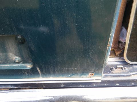 1981 Ford E350 - A close-up view of a vehicle's side panel shows some wear and tear, including a small area of rust.