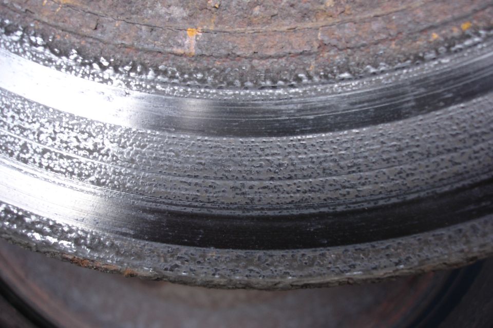 Close-up of a rusty and pitted brake rotor with visible wear marks