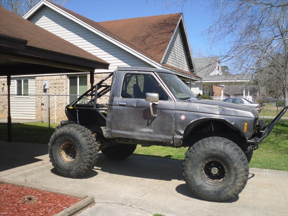 Modified pickup truck with roll cage and oversized tires, side view