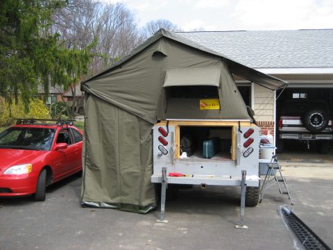 1996 Ford Bronco - A tent trailer is set up in a driveway next to a red car, with a black SUV visible in the garage.