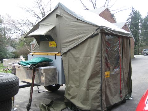 1996 Ford Bronco - A pop-up camper trailer is set up in a driveway, with a tent extension and storage compartments visible.