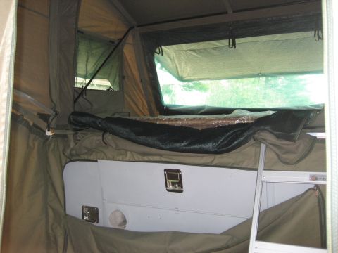 1996 Ford Bronco - The interior of a pop-up camper tent shows a sleeping area and storage solutions.