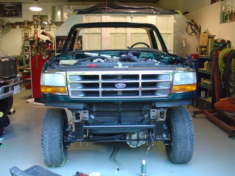 1995 Ford Bronco - Front view of a green 1995 Ford Bronco with its hood open, parked inside a garage.