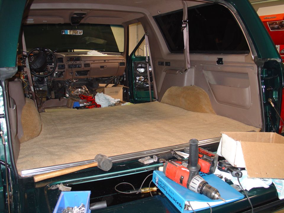 1995 Ford Bronco interior with dashboard removed and cargo area empty, tools visible