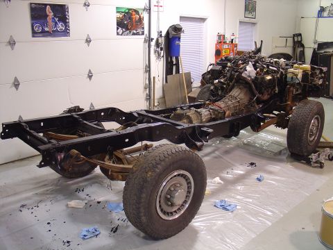 1995 Ford Bronco - The chassis of a vehicle, including the engine and transmission, is shown in a garage setting.