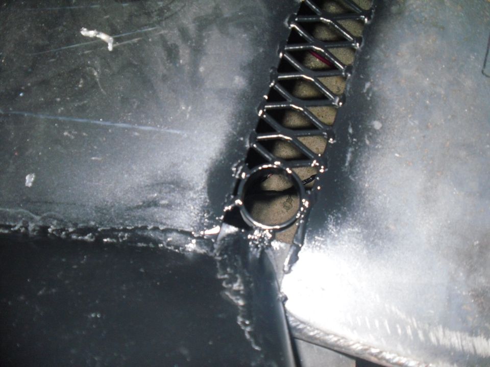 Close-up of a metal cage structure with diamond-shaped openings and a circular tube