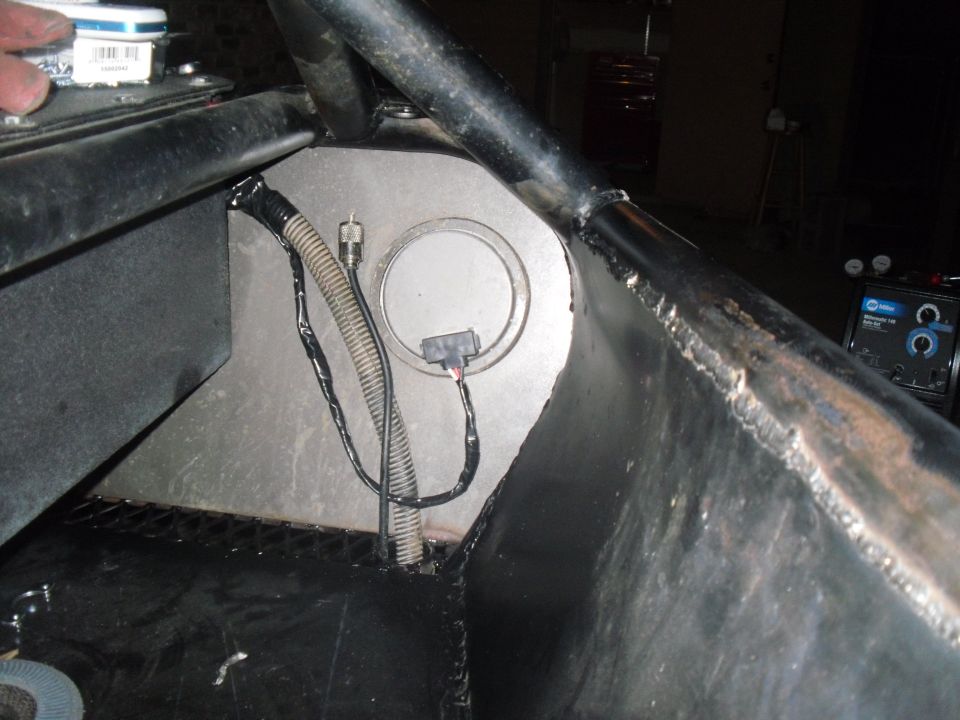 Vehicle interior with a metal fuel tank housing, electrical wiring, and a roll cage tube