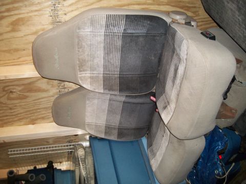 1990 Ford Explorer - Vehicle seats with a plaid pattern are stored indoors, leaning against wooden walls.