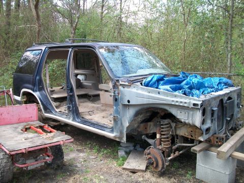 1990 Ford Explorer - The body of a 1990 Ford Explorer is shown disassembled, with its doors removed and the front end stripped bare.