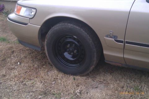2000 Mercury Grand Marquis - Front fender and wheel of a gold 2000 Mercury Grand Marquis, a '4.6' badge on the side.
