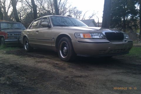 2000 Mercury Grand Marquis - A tan 2000 Mercury Grand Marquis is parked next to another vehicle.