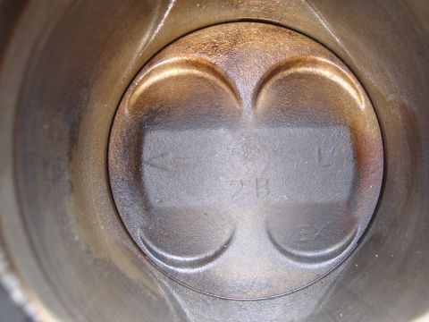 1989 Ford Taurus - Close-up view of a piston top within a cylinder, showing valve reliefs and identifying marks.
