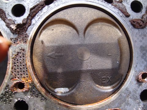 1989 Ford Taurus - Close-up of an engine piston showing valve reliefs and markings. The registry information for a 1989 Ford Taurus is likely incorrect.