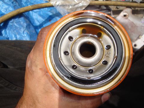 1989 Ford Taurus - A person holds a used oil filter, showing the metal end with a rubber gasket and oil residue.