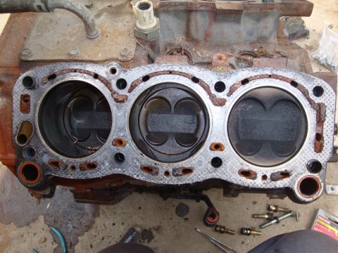 1989 Ford Taurus - Disassembled engine block showing pistons and a damaged head gasket, indicating internal engine issues.