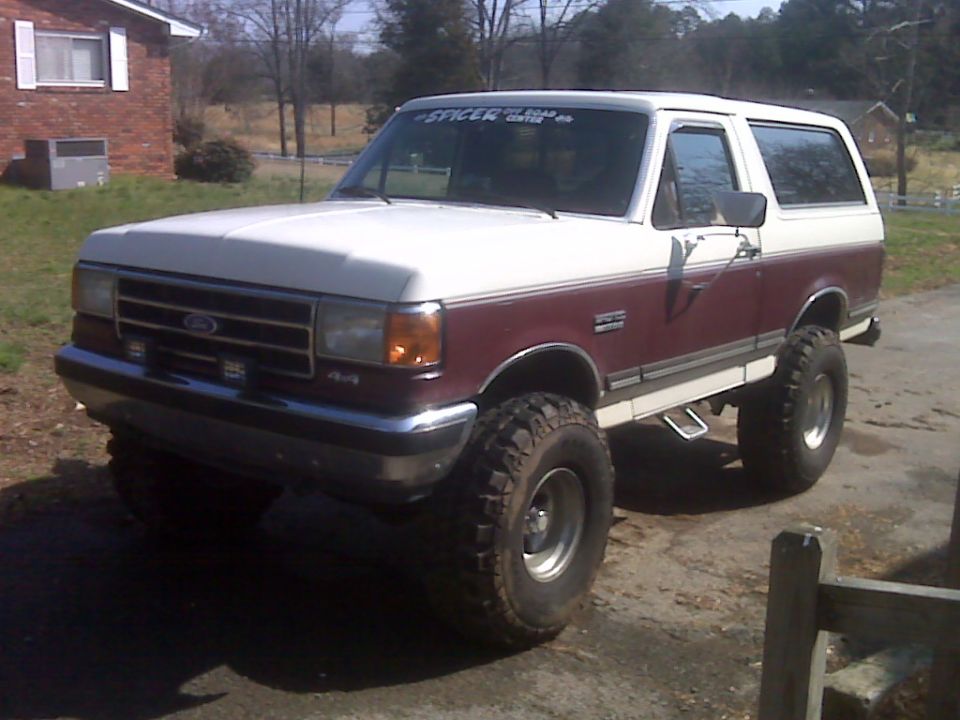 1990 Ford Bronco lifted with large tires, two-tone paint