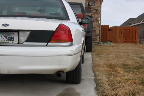 1998 Ford Crown Victoria - A white Ford Crown Victoria is parked next to a dark SUV in a driveway.