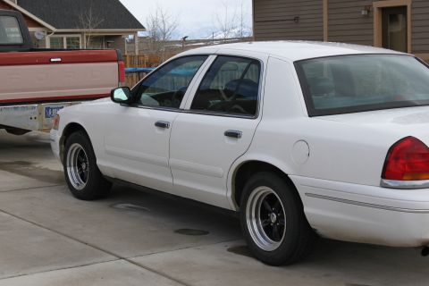 1998 Ford Crown Victoria - A white 1998 Ford Crown Victoria sedan is shown from the side, towing a red pickup truck.