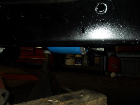 1997 Ford Ranger - The underside of a vehicle is shown, supported by jack stands, with a blue component visible in the background.