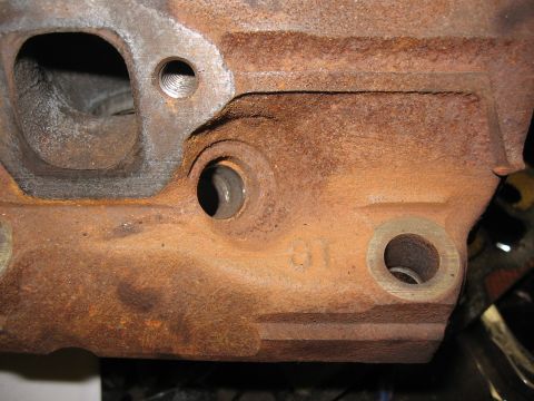 1994 Ford Bronco - Close-up of a heavily rusted engine block, showing cast details and bolt holes.