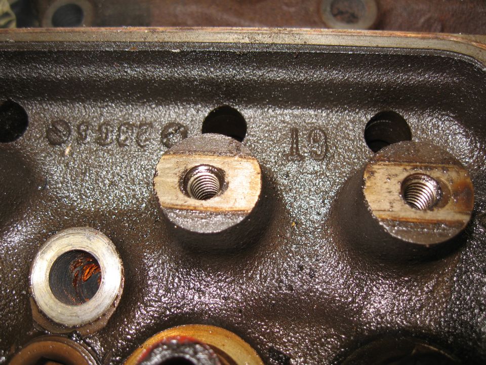 Close-up of an engine cylinder head with cast numbers and bolt holes