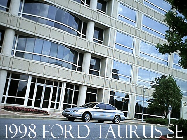 Silver 1998 Ford Taurus SE sedan outside a glass office building with title text overlay