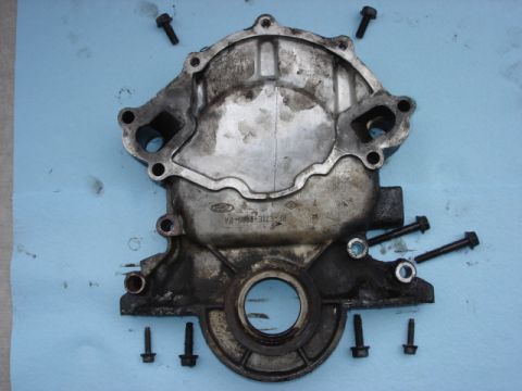 1992 Ford Bronco - A Ford engine timing cover is shown disassembled with bolts arranged around it.