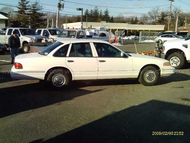 White 1997 Ford Crown Victoria parked next to a white pickup truck