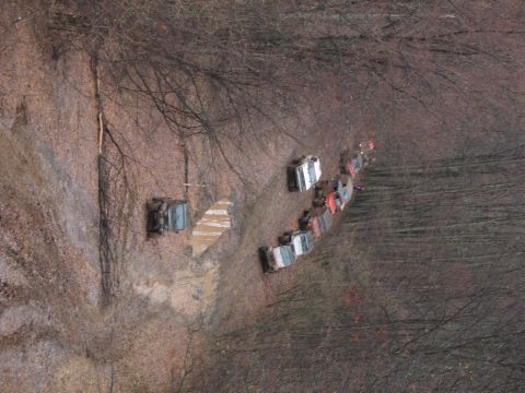 1985 Ford Bronco - A convoy of off-road vehicles navigates a muddy path through a wooded area.