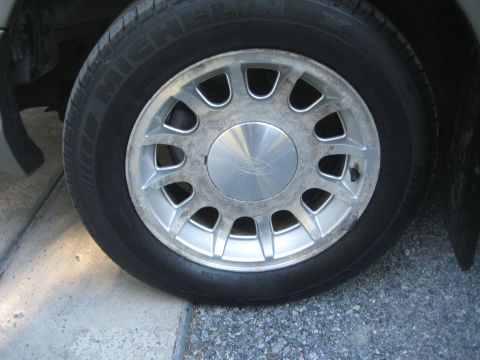 1999 Ford Crown Victoria - Close-up of a car wheel and tire, with a visible Ford logo on the hubcap.
