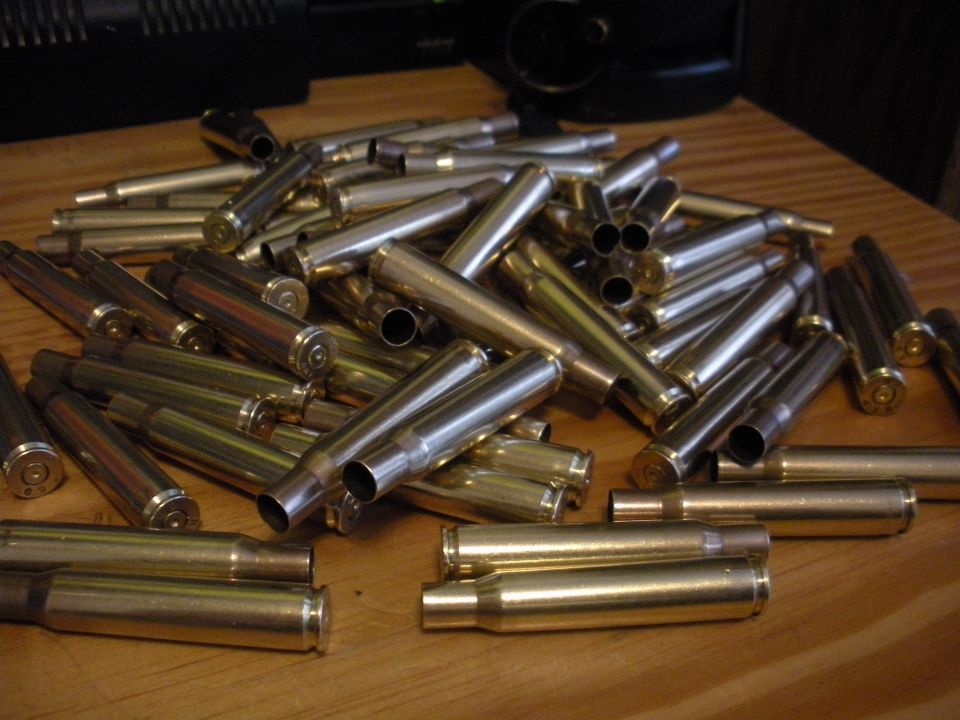 Pile of spent brass shell casings on a wooden surface