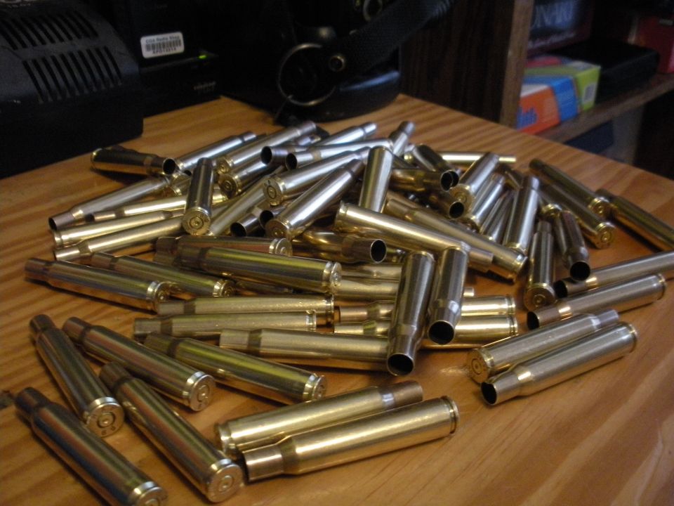 Pile of brass and silver spent shell casings on a wooden table