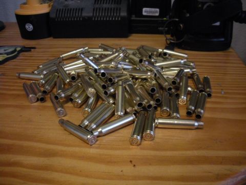 1996 Ford Bronco - A large quantity of spent bullet casings are scattered on a wooden table. Other items are visible in the background.