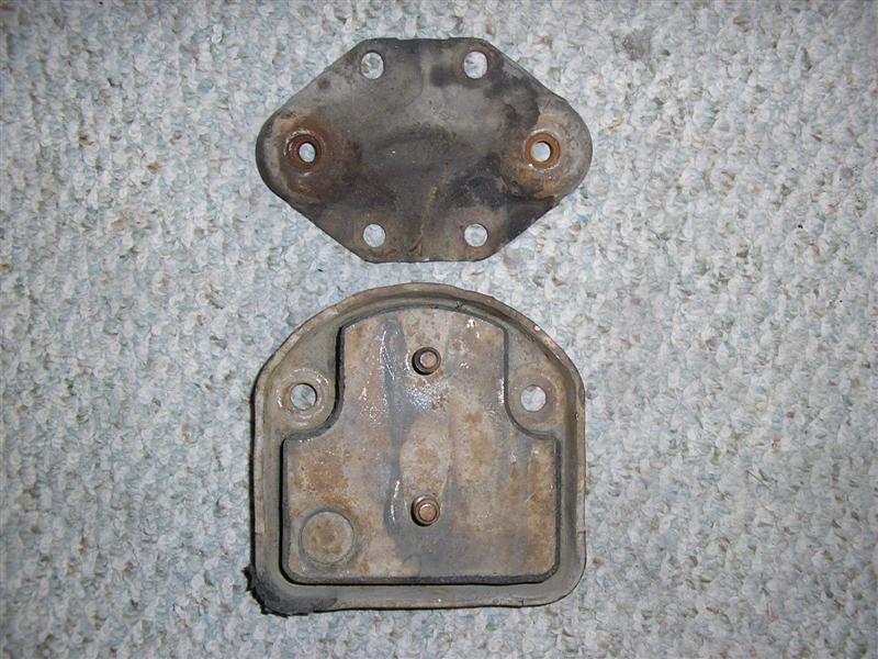 Two rusty metal automotive parts on a carpeted surface