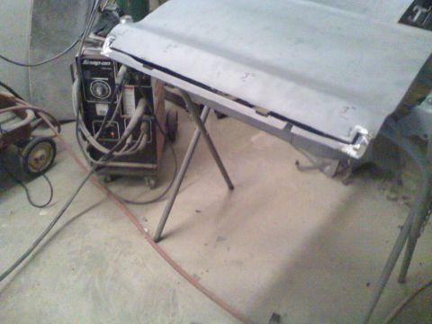 1979 Ford F-250 - A car hood is propped up on sawhorses in a workshop, with welding equipment visible in the background.