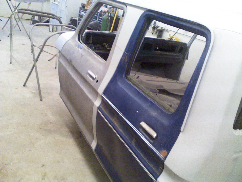 1979 Ford F-250 cab, primer and blue paint, doors open, in a workshop