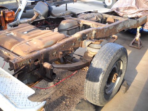 1954 Ford F-100 - The chassis of a vintage truck, showing significant rust and wear, is supported by jack stands.