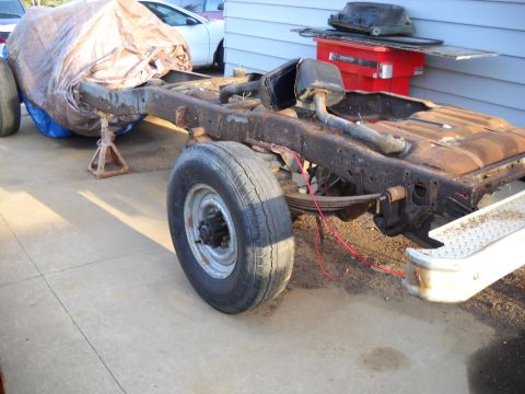 1954 Ford F-100 - The chassis of a 1954 Ford F-100 pickup truck is shown, with the front end covered by a tarp.