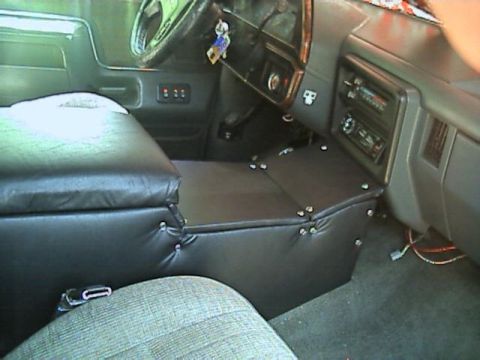 1989 Ford Bronco - Wide interior view of a truck cab with a shop-built black vinyl center console running from under the dash to between the seats, fastened w…