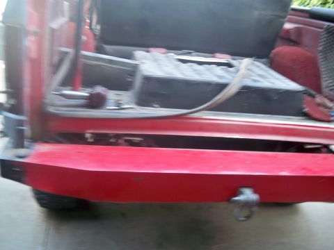 1985 Ford Bronco - The rear of a red vehicle is shown, focusing on the bumper and the open cargo area.