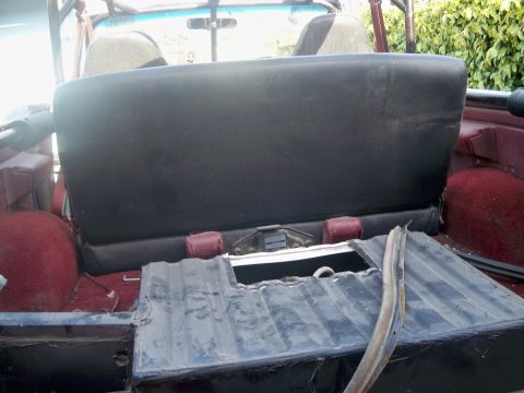 1985 Ford Bronco - Interior view of a vehicle's rear seat and cargo area, showing worn upholstery and an open compartment.